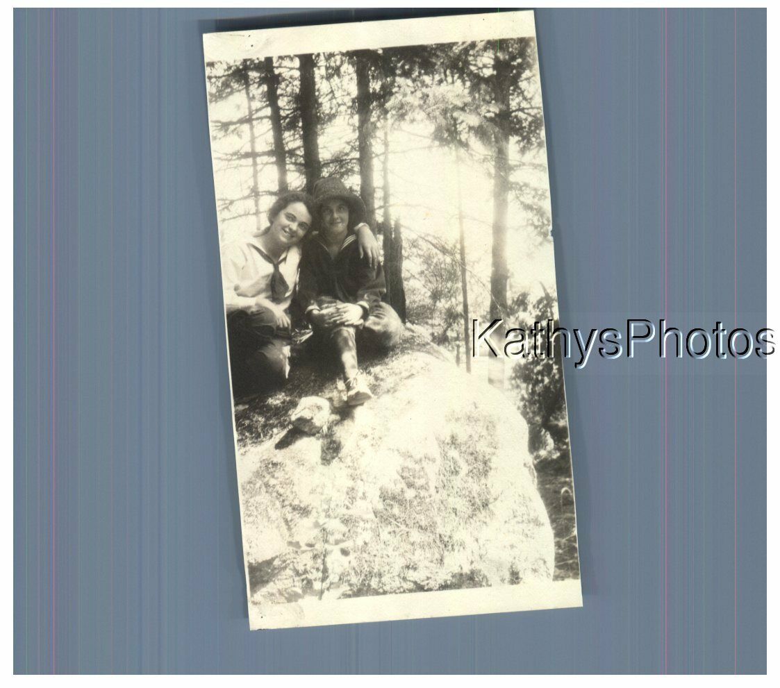 FOUND B&W PHOTO H_5085 TWO GIRLS SITTING ON A ROCK IN A WOODED AREA