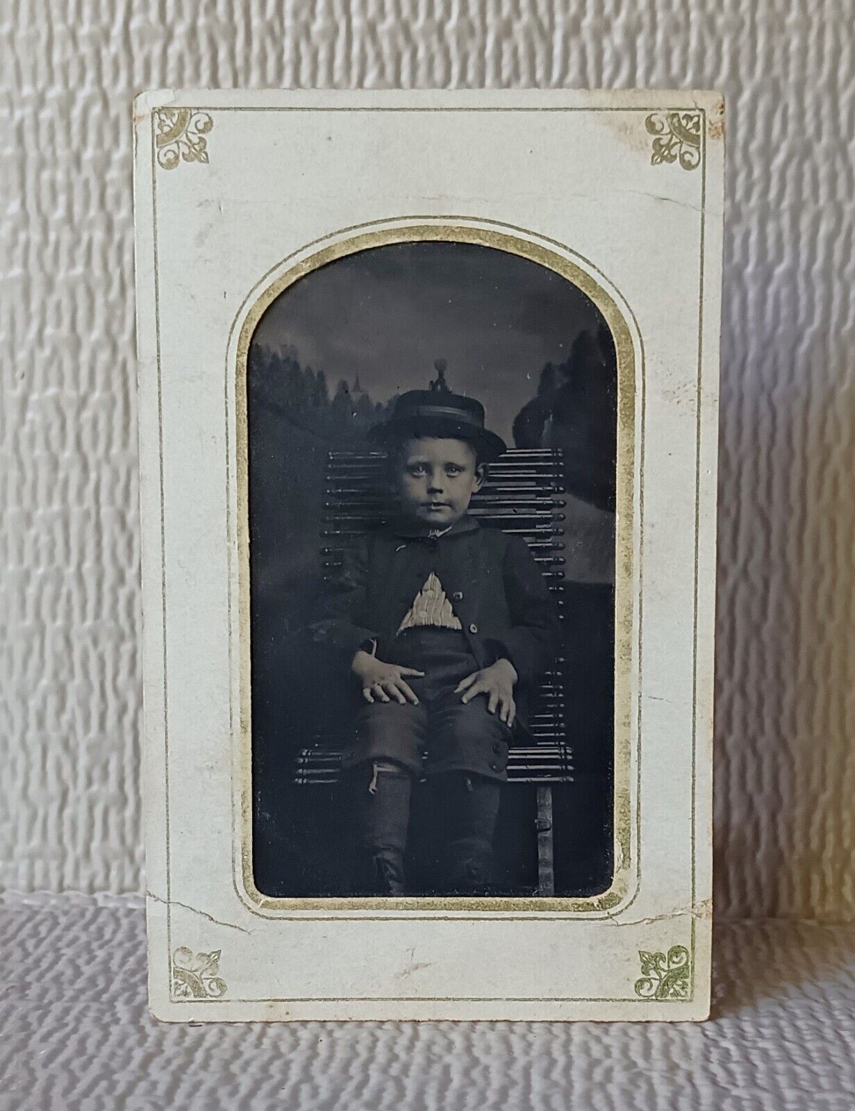 Tintype.    Young Boy lying back in chair looking comfortable posing for camera