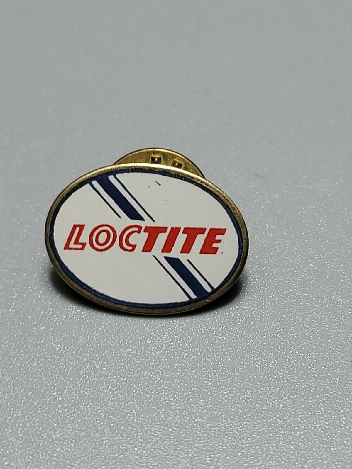 Vintage LOCTITE Pin oval white w/blue stripe on gold tone lapel pin w/backing #1
