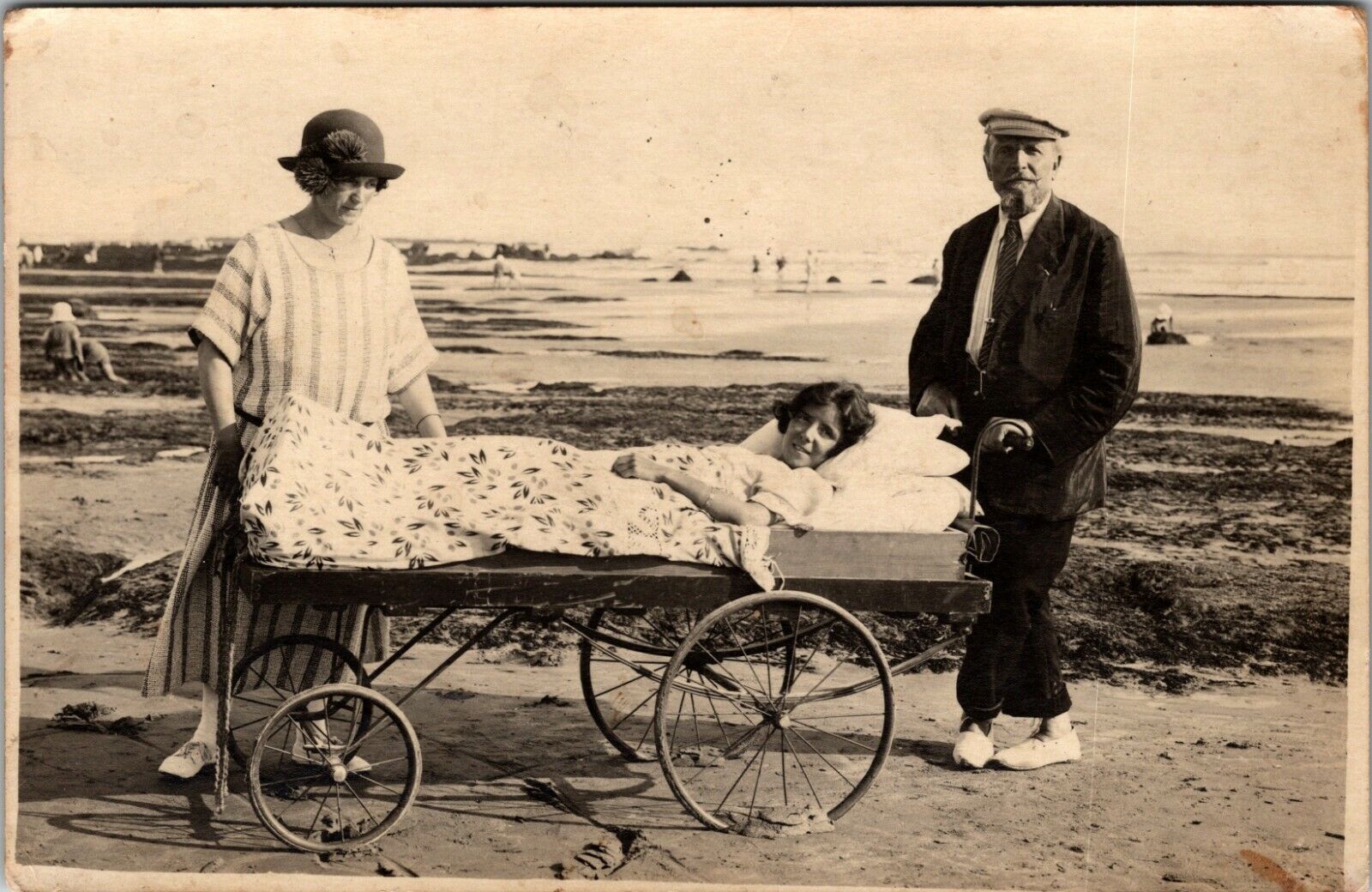 YOUNG BEDRIDDEN WOMAN AT THE BEACH : MOBILE HOSPITAL BED : SPANISH FLU