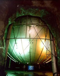 KamLAND consists of a weather balloon, 13 meters (43 feet) in diameter, filled with about a kiloton of liquid scintillator, a chemical soup that emits flashes of light when an incoming anti-neutrino collides with a proton. These light flashes are detected by a surrounding array of 1,879 photomultiplier light sensors which convert the flashes into electronic signals that computers can analyze. 