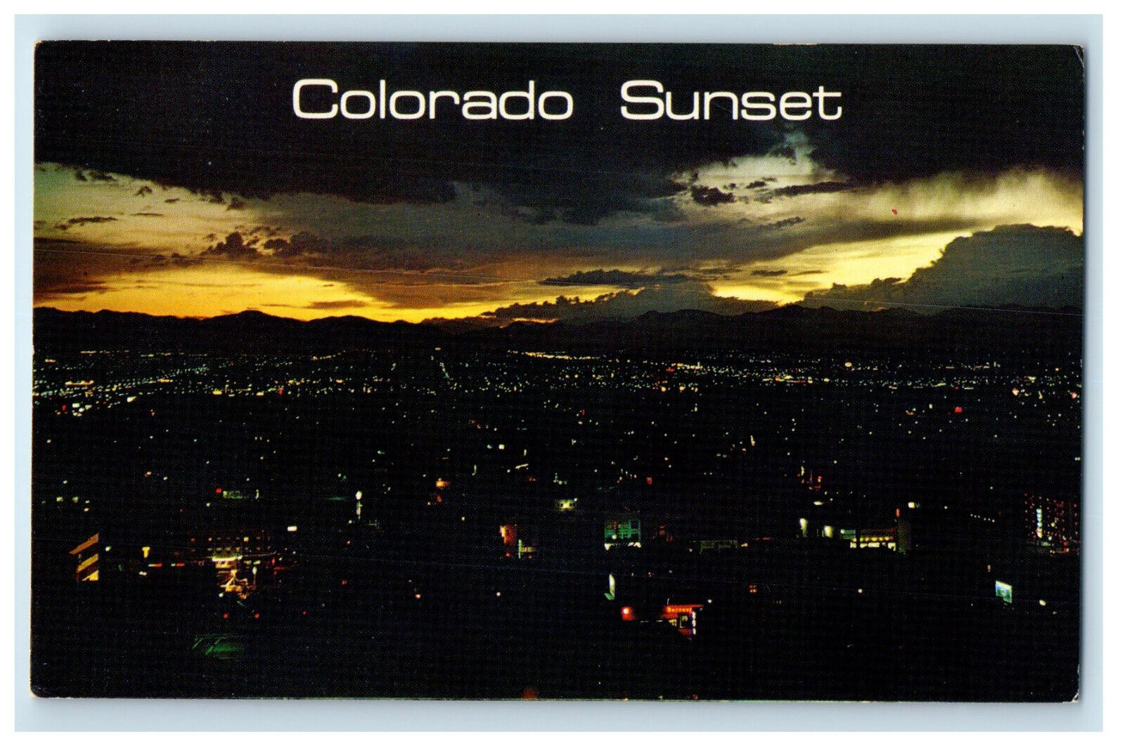 c1960s Sunset Over West Denver, Sets Behind The Rocky Mountains CO Postcard
