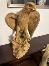 Handcrafted wooden sculpture of an eagle perched on a rocky base with fish/prey picture